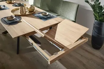 Esstisch mit Massivholztischplatte, bei dem die Verlängerung ausgezogen ist.
