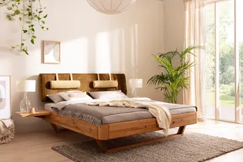 Bett mit Kopfteil aus grünem Stoff an dem zwei Nackenrollen befestigt sein, der Rahmen ist aus Massivholz in einem lichtdurchfluteten Schlafzimmer mit Pflanzen.