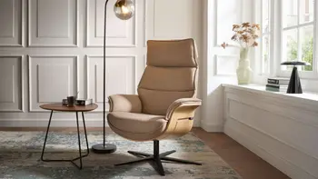 Design Relaxsessel mit beigem Leder und heller Holzschale an den Armlehnen.