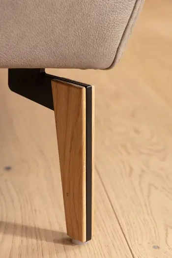 Silberner Metallfuß eines grauen Ledersofas.