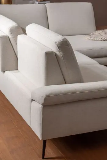 Rückansicht eines hellbeigen Ecksofas mit schwarzen Metallfüßen.