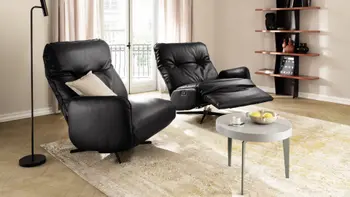 Zwei schwarze Ledersessel die nur auf jeweils einer Seite eine Armlehne haben, der rechte Sessel ist nach hinten gelehnt in Relaxposition.