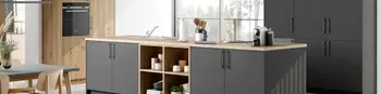 Anthrazitfarbene Küche mit Kücheninsel und Holzdetails. Der Schrank links im Bild ist ganz in Holzoptik und hat einen erhöhten Backofen. Auf der Kochinsel ist ein Waschbecken wie auch das Kochfeld integriert.&nbsp;