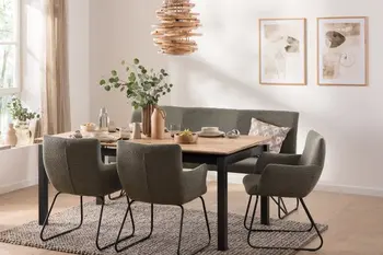 Modernes Esszimmer mit einem Massivholzesstisch aus Eiche, der ein schwarzes Metallgestell hat und um den herum moderne Schalenstühle und Sitzbank in grün mit Metallgestell stehen.