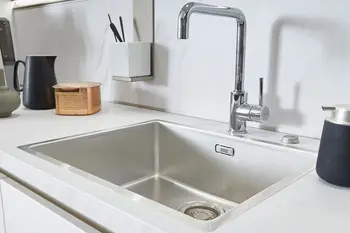 Edelstahlspüle in einer Küche mit weißer Arbeitsplatte.