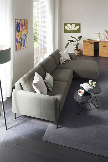 Vogelperspektive auf grünes Ecksofa in gemütlichem Wohnzimmer.