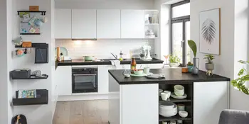 Helle kompakte Inselkueche mit schwarzer Steinarbeitsplatte.