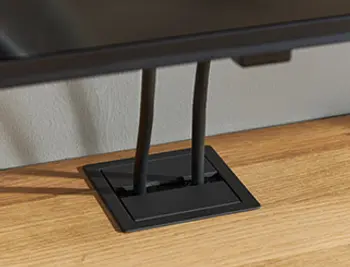 Praktischer Kabeldurchlass in schwarzer Ausführung – sauber integrierte Kabelführung auf einer Eichenholz-Oberfläche für moderne TV- und Mediamöbel.