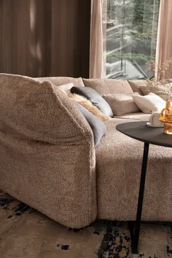 Geknickte Armlehne eines beigen Design Sofas.