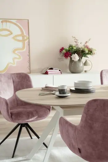 Armlehnstuhl bezogen mit Stoff in Rosa und schwarzem Metall Fußgestell an einem Esstisch mit Holztischplatte an dem ein weiterer rosa Armlehnstuhl steht.