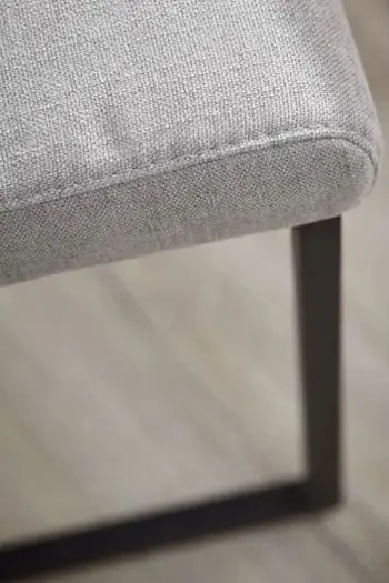 Teile der Sitzfläche eines grauen Stuhls mit schwarzem Fußgestell.