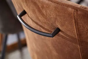 Rückenlehne eines Esszimmerstuhls in rostrot, an dem ein schwarzer Griff aus Metall ist.