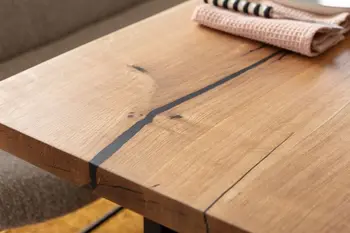 Tischplatte aus massiver Eiche mit Epoxidharz in den Baumlöchern.