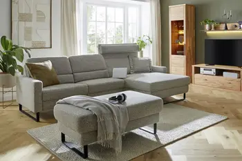 Ein graues Ecksofa mit klappbaren Kopfstützen.