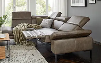 Olivgrünes Ledersofa mit hochgeklappter Fußlehne und zurückgeklappter Rückenlehne.