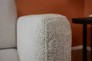 Detailansicht der Armlehne eines beigen Sofas.