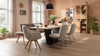 Gemütliches Esszimmer in warmen Tönen mit großem Esstisch, beigen Polsterstühlen und Schrankwand aus Massivholz.