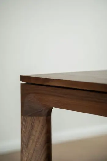 Nahansicht der Tischkante eines Esstisches aus Nussbaumholz.