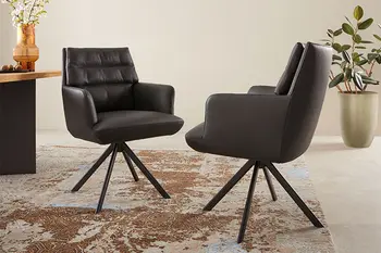 Zwei Esszimmersessel mit Armlehnen in schwarzem Leder stehen sich gegenüber.