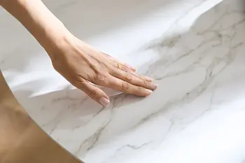 Frau streicht mit Hand über hochwertige Keramiktischplatte in Marmoroptik.