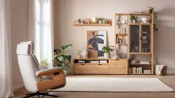 Harmonisch eingerichtetes Wohnzimmer mit moderner Wohnwand aus Eiche, Relaxsessel und beigem Teppich.