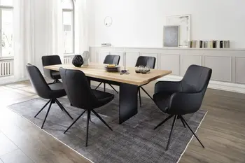 Modernes Esszimmer, in dem ein Designer Esstisch aus Massivholz mit Metallfuß in schwarz steht, um den Tisch stehen moderne schwarze Schalenstühle mit und ohne Armlehne.