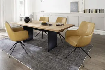 Moderne gelbe Armlehnstühle mit schwarzem Metallgestell um einen Massivholz Esstisch in einem hellen Esszimmer.