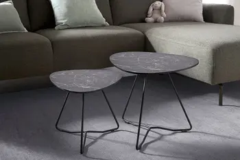 Zwei schwarze Beistelltische mit schwarzem Metallgestell vor einem Sofa.