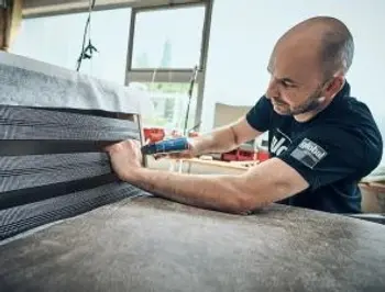 Mann in einer Produktionsstätte von global Wohnen der ein Möbelstück montiert.