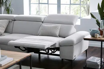 Hellgraues Sofa mit hochgeklappter Fußstütze und nach hinten geklappter Rückenlehne.