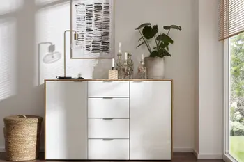 Kommode aus weißem Lack, dekoriert mit Kerzenhalter, Grünpflanze und einer modernen Tischlampe.