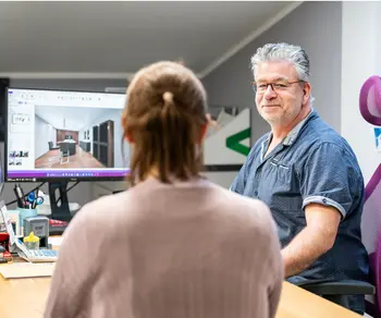 Beratungsgespraech mit Kundin mit Praesentation von 3D-Kuechenmodell.