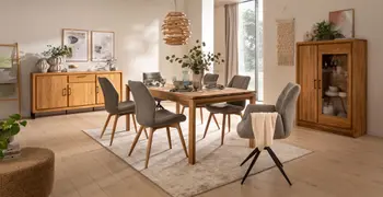 Moderne graue Stühle mit holzgestell und zwei graue Armlehnstühle mit schwarzem Metallgestell um einen Massivholzesstisch.