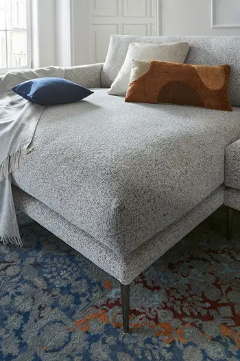 Longchair eines grauen Design Sofas mit filigranen Füßen.