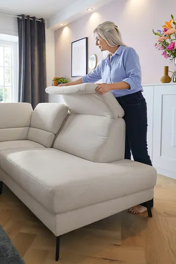 Eine Frau reinigt den Stoff einer Kopfstütze eines Sofas