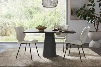 Beige Design Esszimmerstühle mit schwarzem Gestell um einen schwarzen Esstisch.