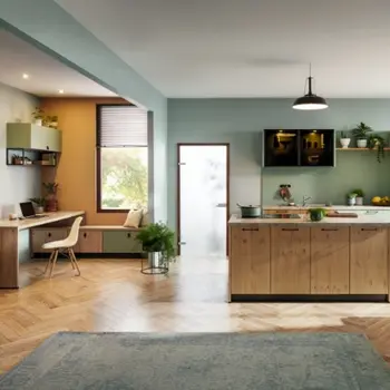 Kombination aus Essen und Arbeiten, Links ein Büroschreibtisch und Stuhl und recht in optisch passendem Look eine Küche mit Insel in Holzoptik.