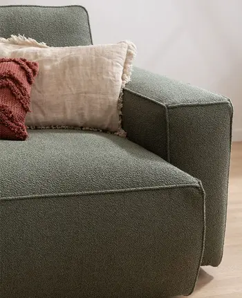 Detailbild von Armlehne und Sitzpolster eines Sofas mit grünem Stoffbezug.