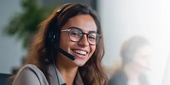 Glückliche Geschäftsfrau mit Headset lacht in die Kamera.