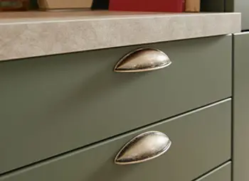 Schubladen und Arbeitsplatte einer grünen Landhausküche im Detail.