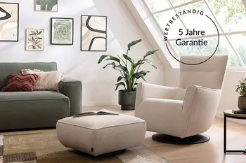 Grünes Sofa mit hellem Sessel und Fußhocker in einem hellen wohnzimmer. Rechts oben befindet sich ein Vermerk auf die 5 Jahre Garantie.