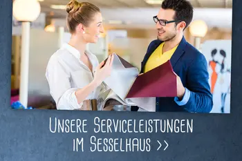 Ein Berater und eine Kundin betrachten gemeinsam Stoffproben in einem Möbelhaus.