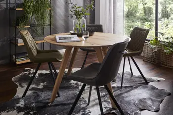 Kleiner runder Esstisch aus Massivholz mit vier Stühlen in grüntönen mit Steppung an der Rückenlehne in einem Esszimmer mit vielen Pflanzen.