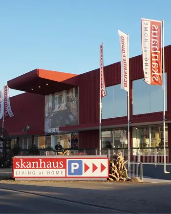 Hausfassade von Möbel Skanhaus mit Flaggenmasten und Firmenschild.