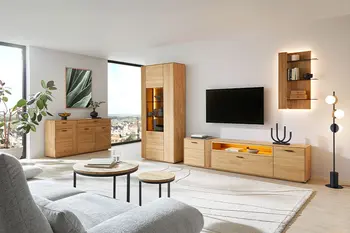 Helles Wohnzimmer mit moderner Wohnzimmerwand aus Eiche, beigem Teppich und hellgrauem Sofa. 