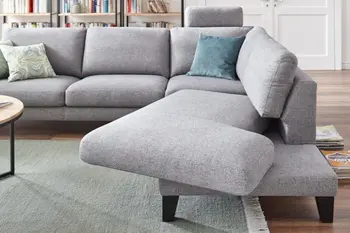 Graues Ecksofa mit breitem Longchair, der  nach vorne drehbar ist.
