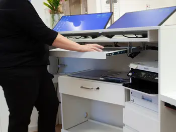 Mitarbeiterin am Tresen, arbeiten an angewinkelten Bildschirmen für ein ergonomisches und gesundes Arbeiten