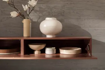 Hängendes Lowboard aus Nussbaum, bei dem die Türe nach unten geklappt ist.