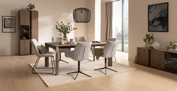 Schalenstühle mit hellem Stoff bezogen mit und ohne Armlehne und mit schwarzem Metallgestell um einen dunkeln Holztisch in einem hellen modernen Esszimmer.