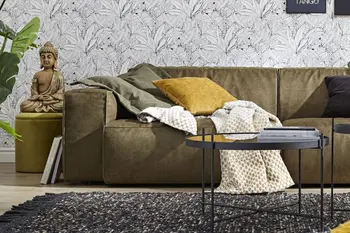 Modernes grünes Ecksofa mit niedriger Rückenlehne, dekoriert mit grünem und gelbem Kissen sowie einer gemusterten Wolldecke.